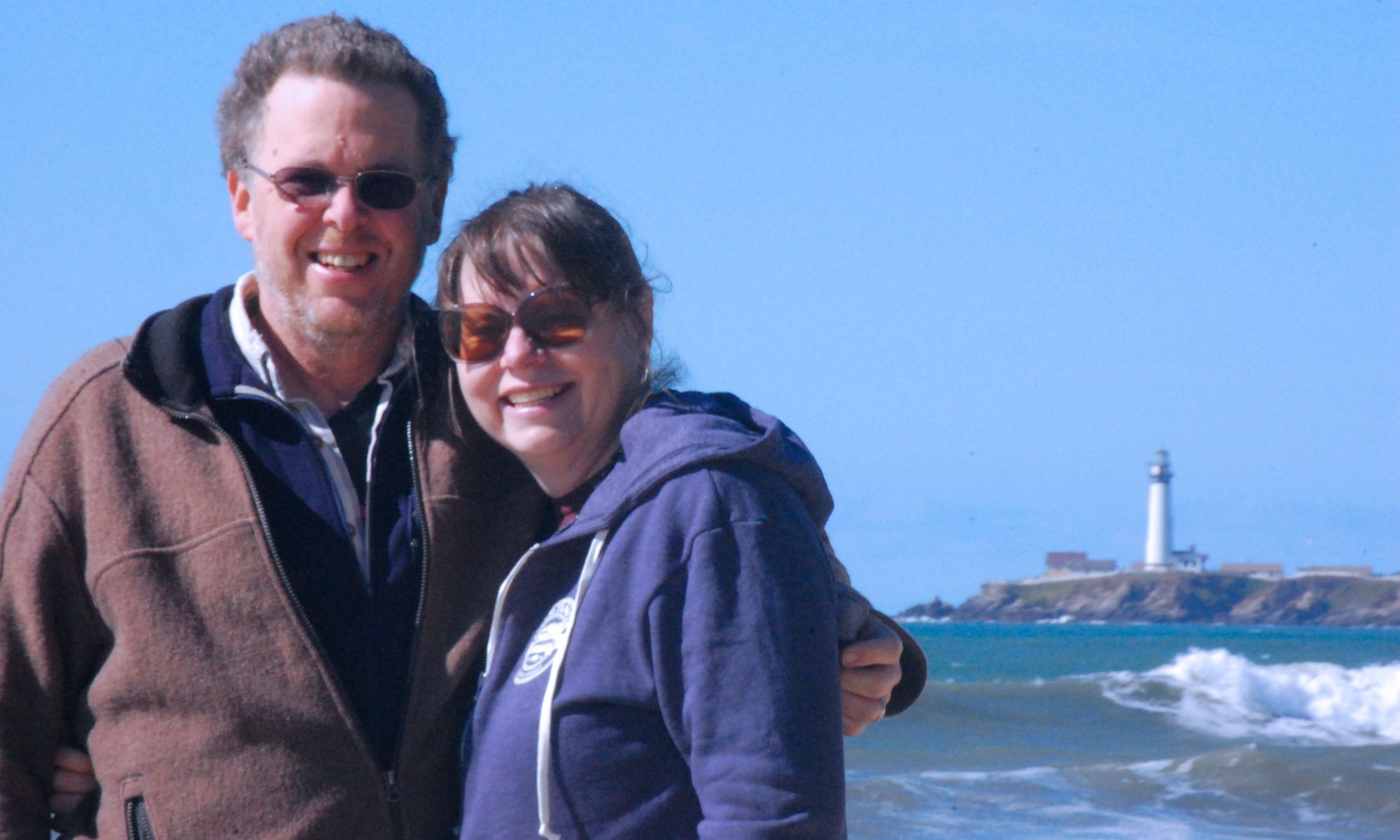 photo of Lee and Katie at the the beach with lighthouse in background
