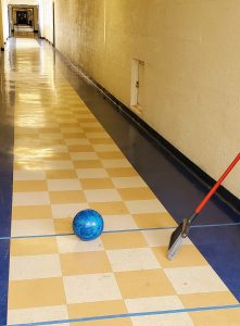 photo showing a bowling ball and broom in a hallway