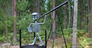 photo of a metal sculpture representing a person with a telescope on a tripod.