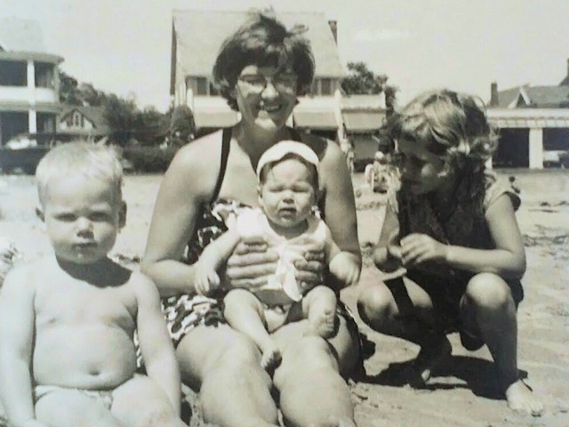 Photo of three kids and a woman on the beach.